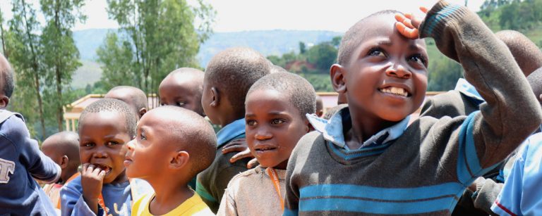 Burundian Schoolchildren outside gathered and smiling, looking in all directions