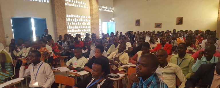 Many people crowded into a room listen to a lecture