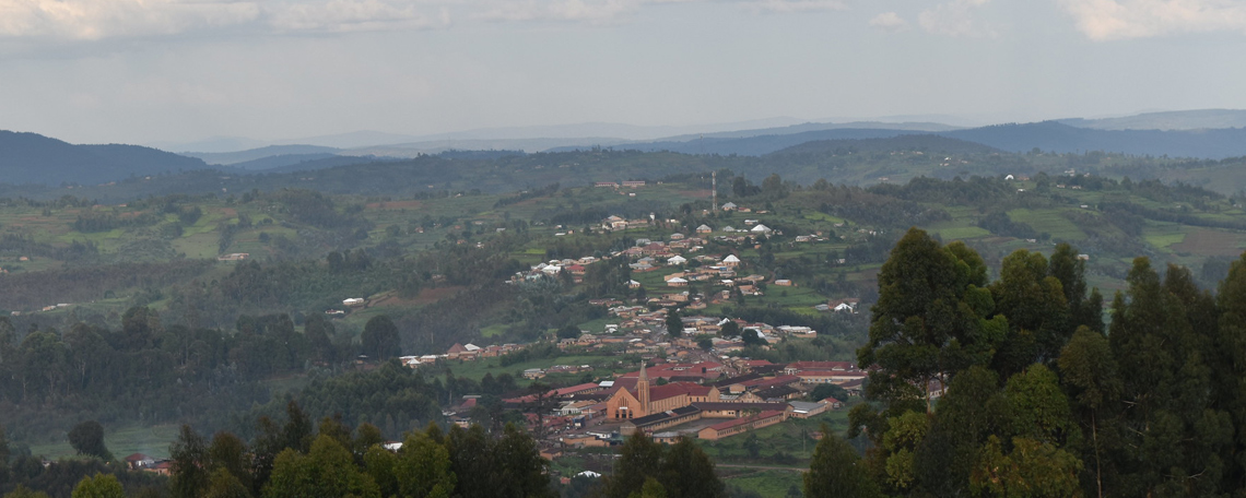 a view of a village from a hill, set amongst green valleys
