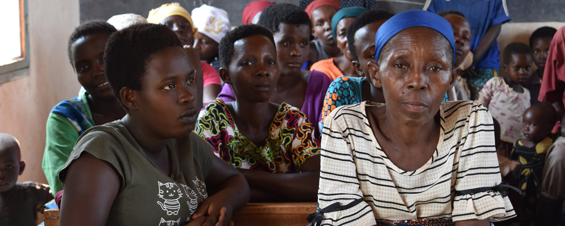 A group of women in a classroom are listening, one woman looks directly at the camera