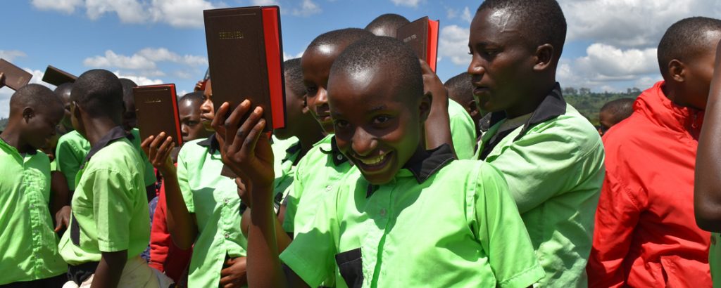 a schoolgirl holds up her new bible smiling
