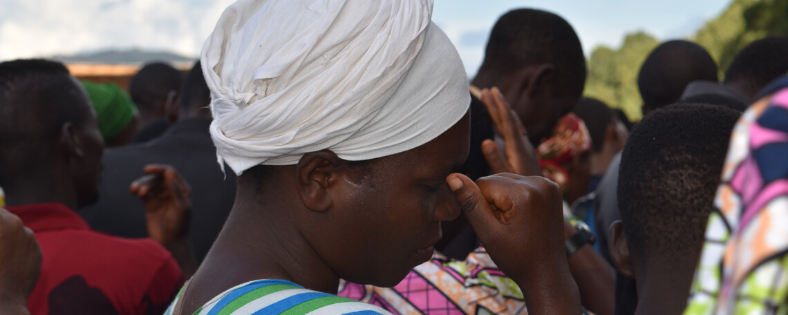 a lady with a white headscarf reflects amongst a crowd