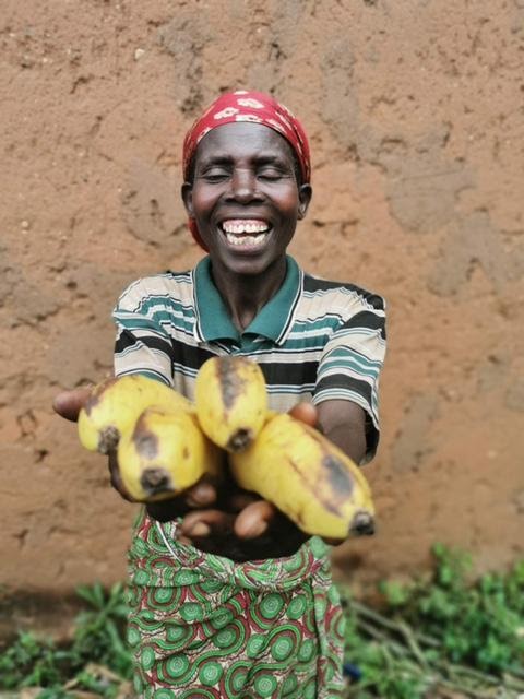 Odette laughs with joy as she holds out her crop of bananas